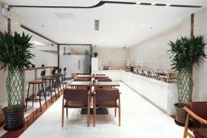 un restaurante con mesas de madera, sillas y plantas en Lavande Hotel Beijing Guanganmen Daguan Garden en Pekín