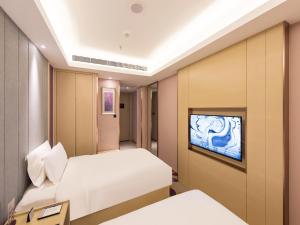 a hotel room with two beds and a flat screen tv at Lavande Hotel Beijing Railway Station in Beijing