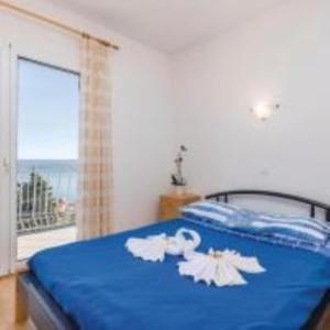 Schlafzimmer mit einem blauen Bett und einem großen Fenster in der Unterkunft Holiday Home Sea view in Brseč
