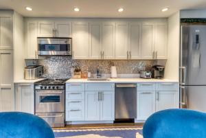 uma cozinha com armários brancos e cadeiras azuis em Provincetown Waterfront Studio em Provincetown