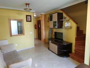 sala de estar con sofá, TV y escaleras en Apartamentos - El Bosquin, en Nueva de Llanes