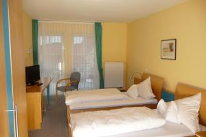 a hotel room with two beds and a desk at Hotel Bachwiesen in Langensendelbach