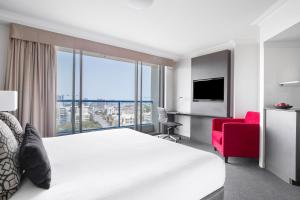 a hotel room with a bed and a red chair at Mantra on Queen in Brisbane +20 photos