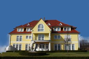 a large yellow house with a red roof at Hotel Bachwiesen in Langensendelbach