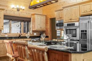 een keuken met houten kasten en een bar met wijnglazen bij Spa Luxury in an Expansive Cabin Escape! in Nisswa
