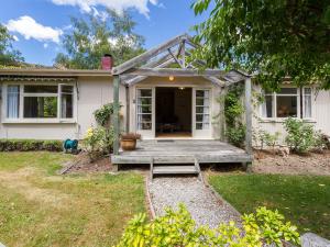 a house with a wooden porch with a bench at Arrow Bach - Arrowtown Holiday Home in Arrowtown