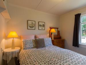 a bedroom with a bed with two lamps and a window at Arrow Bach - Arrowtown Holiday Home in Arrowtown