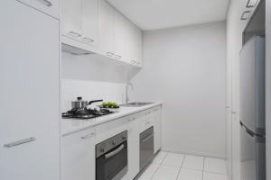 a kitchen with white cabinets and white appliances at Mantra Midtown in Brisbane