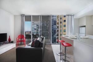 a living room with a couch and a kitchen with a view at Mantra Midtown in Brisbane