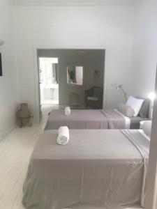 een witte kamer met 2 bedden en een bank bij Byron Springs in Byron Bay