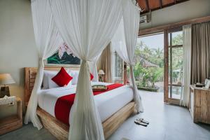 a bedroom with a canopy bed with red and white pillows at Kawi Resort Ubud in Tegalalang +92 photos