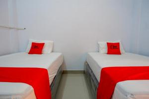 2 camas con almohadas rojas en una habitación en RedDoorz near Lokawisata Baturaden 2, en Tenjo