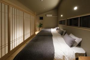 2 camas en una habitación con ventanas grandes en Kamome Jyuku, en Takamatsu