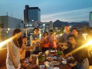 a group of people standing around a table on a rooftop at Insadong Hostel in Seoul