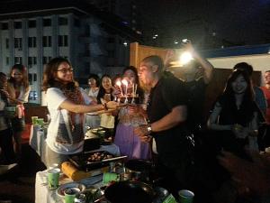 a group of people standing around a table with a cake with lit candles at Insadong Hostel in Seoul