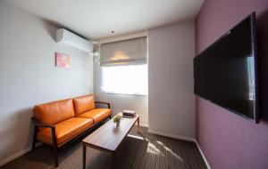 a living room with an orange couch and a table at GRAND BASE Kurashiki Chuo in Kurashiki