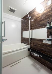 een badkamer met een bad en een houten muur bij GRAND BASE Kurashiki Chuo in Kurashiki