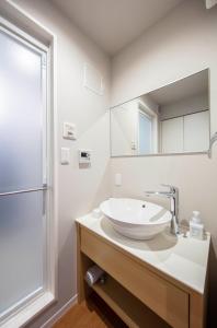 La salle de bains blanche est pourvue d'un lavabo et d'un miroir. dans l'établissement GRAND BASE Kurashiki Chuo, à Kurashiki