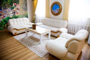 una sala de estar con sofás blancos y una mesa. en Altair Hotel en Shymkent