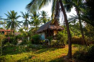 uma pequena cabana com telhado de palha e palmeiras em Retro Kampot Guesthouse em Kampot