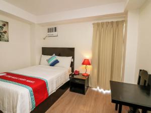 Habitación de hotel con cama y escritorio con lámpara. en The Orient Beach Boracay en Boracay