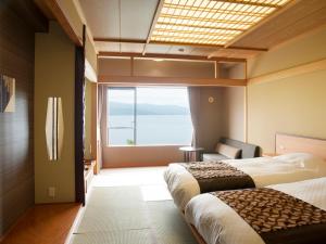 a hotel room with two beds and a large window at Lake Akan Tsuruga Wings in Akankohan