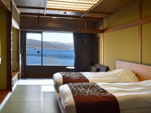 two beds in a room with a view of the water at Lake Akan Tsuruga Wings in Akankohan