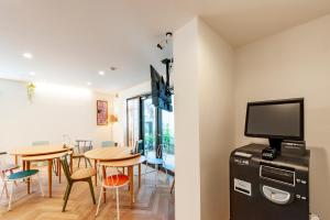a dining room with a table and chairs and a tv at plat hostel keikyu haneda home in Tokyo