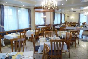 un restaurante con mesas y sillas blancas y una lámpara de araña en Hotel Bachwiesen en Langensendelbach