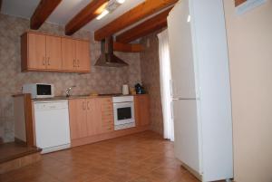 a kitchen with a white refrigerator and wooden cabinets at Casa La Catalina II in Beceite