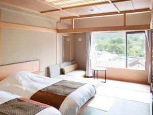 two beds in a room with a large window at Lake Akan Tsuruga Wings in Akankohan