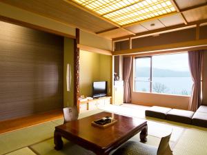 a living room with a table and a large window at Lake Akan Tsuruga Wings in Akankohan
