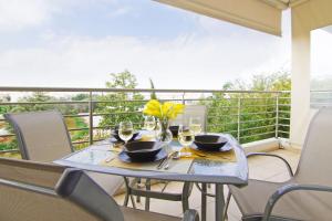 - une table avec des verres à vin et des fleurs jaunes sur le balcon dans l'établissement Apartment Mariada, à Paralímni