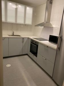 eine Küche mit weißen Schränken, einer Spüle und einem Kühlschrank in der Unterkunft Noah longstay Arboga in Arboga
