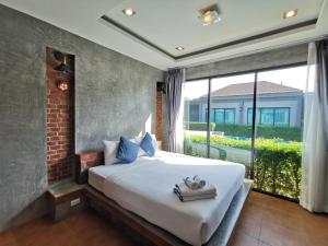 um quarto com uma cama grande e uma janela grande em BaanMee Phuket SHA Plus em Chalong