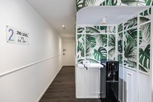 a hallway with a white wall with palm leaves wallpaper at Philip Hotel in Singapore