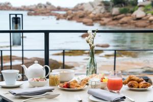 a table with breakfast food and a view of the ocean at Castel Beau Site in Perros-Guirec