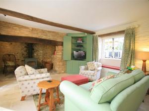a living room with a couch and chairs and a fireplace at Keen Cottage in Kingham