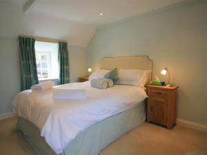 a bedroom with a large white bed with a window at Keen Cottage in Kingham