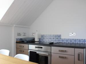 a kitchen with blue and white tiles on the wall at The Eaves in Sandgate
