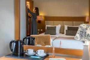 a woman standing in front of a bed in a hotel room at Georgia's Garden by Omilos Hotels in Amoudara Herakliou