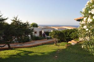 a garden with a house and the ocean in the background at Hotel Club Sunway Punta Prima in Es Pujols