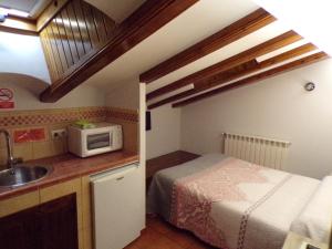 a small kitchen with a bed and a microwave at Hostal Serruchi in Teruel