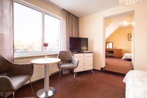 a hotel room with a table and chairs and a television at Dom Gościnny Sand in Rewal