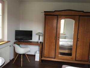 ein Schlafzimmer mit einem Bett und einem Schreibtisch mit einem Fernseher in der Unterkunft Gästehaus am Weiher in Weil am Rhein