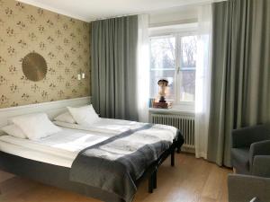 a bedroom with a bed and a window and a chair at Akademihotellet in Uppsala