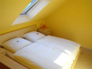 Schlafzimmer mit einem weißen Bett und einem Fenster in der Unterkunft Marcos Heuboden in Oberzissen