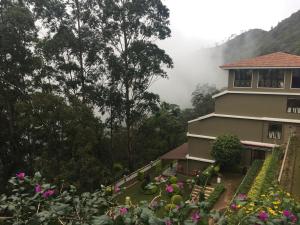 a house in the mountains with flowers in front of it at Abad Copper Castle Resort in Munnar