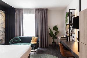 um quarto de hotel com uma cama, um sofá e uma janela em Ariane Hotel em Ieper