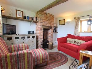 a living room with a red couch and a fireplace at The Shooting Folly in Cheswardine